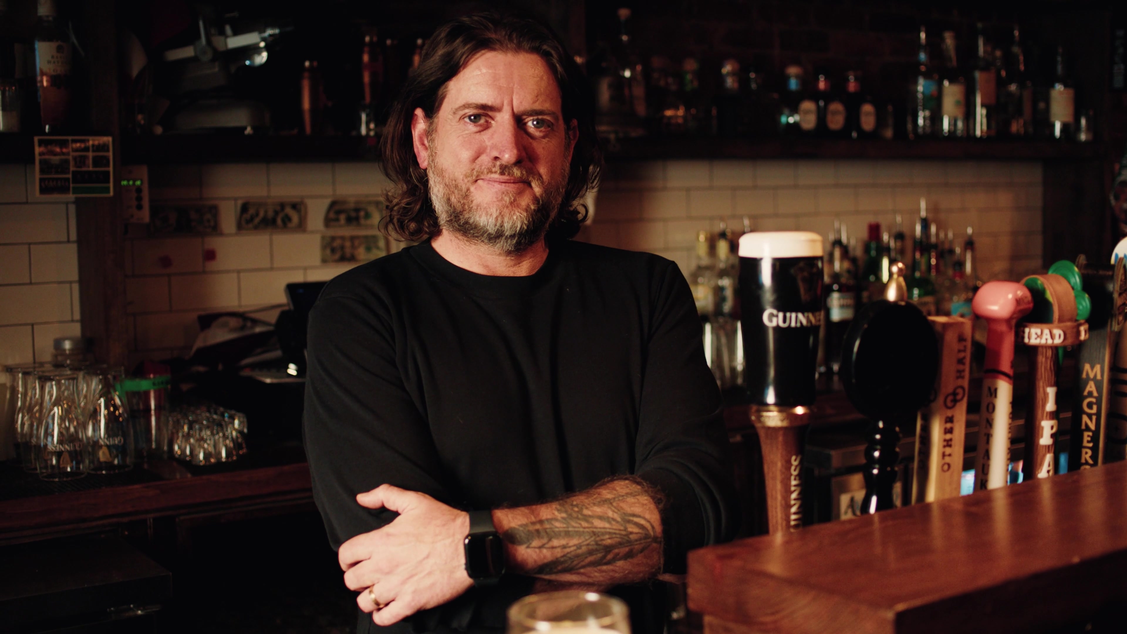 A smiling subject behind the bar in District Stories